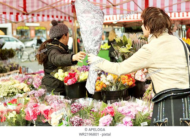 Mature woman buying bouquet at flower stall