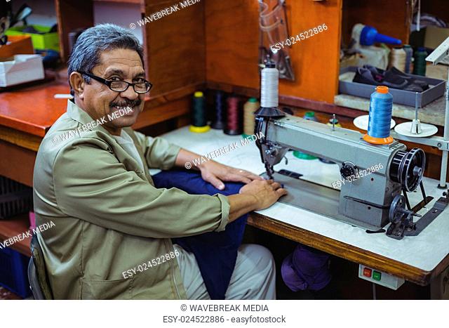 Portrait of smiling shoemaker using sewing machine