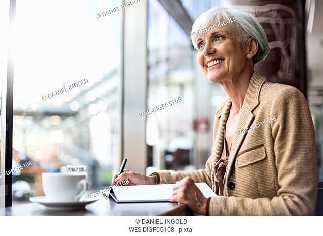 Smiling senior businesswoman taking notes in a cafe