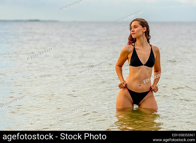 A beautiful Brunette bikini model enjoys the weather outdoors on the beach