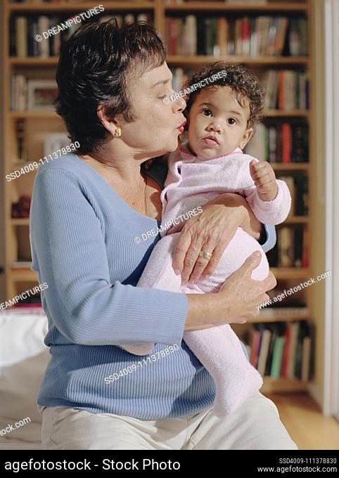 Middle-aged woman kissing her baby granddaughter