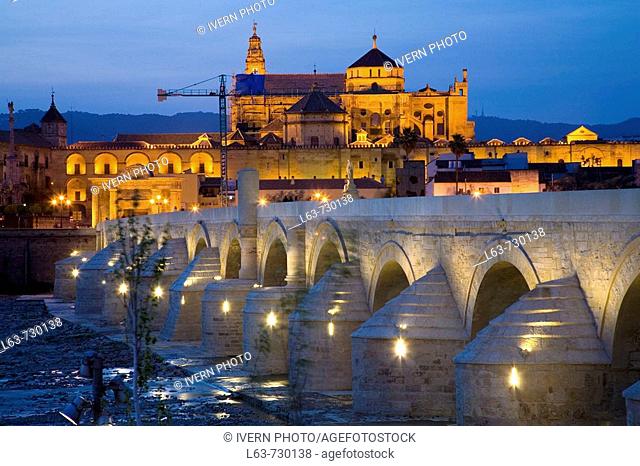 Roman bridge over Guadalquivir river with Great Mosque in background at night, Cordoba. Andalusia, Spain