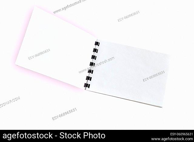 Blank open notebook or brochure with black plastic spiral close up, isolated on light pink background. Diary notepad, paper page organizer or scrapbook - mock...