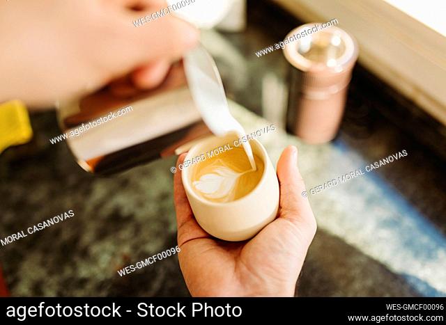 Young man preparing latte in kitchen