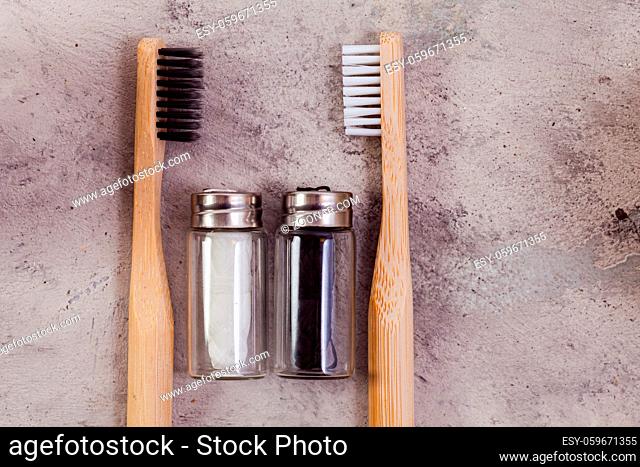 Zero waste self-care products. Black, white bamboo toothbrushe, and flax thread on grey concrete background. Flat lay style
