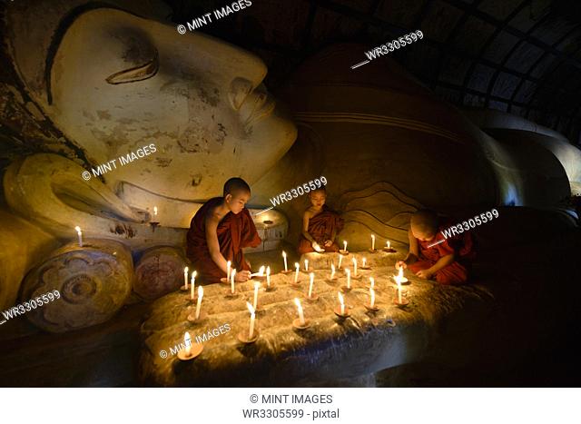 Asian monks lighting candles in temple