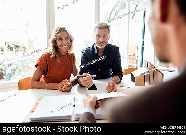 Happy mature woman and man doing paperwork with real estate agent