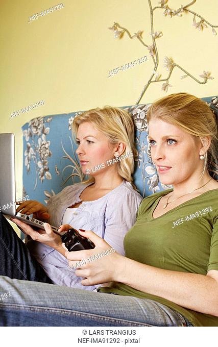 Two young women playing video game in bedroom