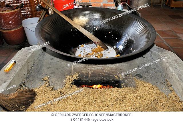 Ingredients, caramel, coconut flakes, for the preparation of puffed rice sweets in a large metal bowl above a fiery furnace, confectionery factory, Vinh Long