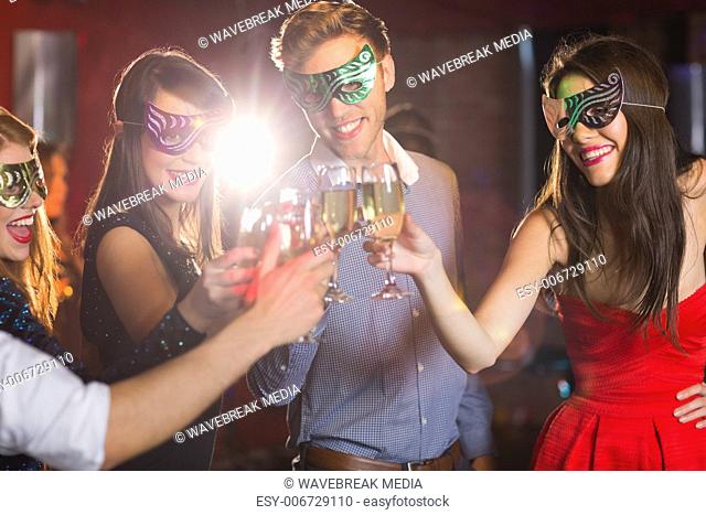 Friends in masquerade masks toasting with champagne