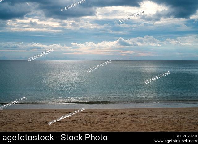 View from sandy beach on dramatic tropical cloudy sky and sea