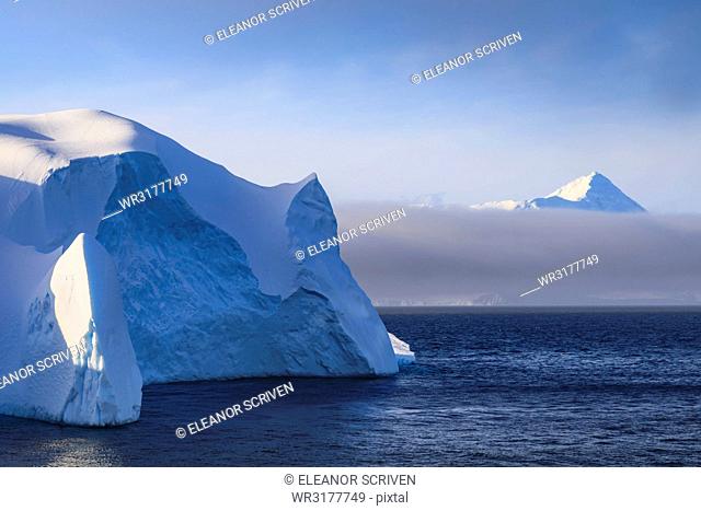 Huge iceberg, and mountain, clearing mist, Bransfield Strait, near South Shetland Islands and Antarctic Peninsula, Antarctica, Polar Regions