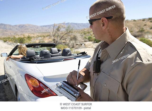 Police officer writing a ticket for a convertible driver