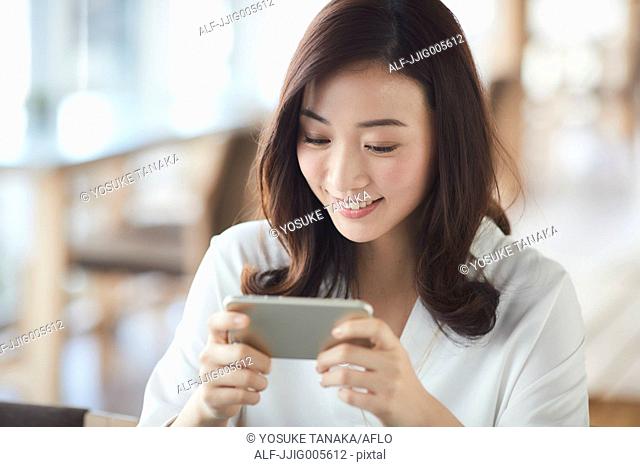 Japanese woman with smartphone in a stylish cafe