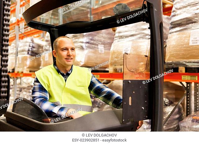 wholesale, logistic, loading, shipment and people concept - smiling man or loader operating forklift loader at warehouse