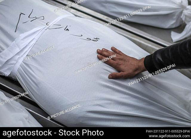 22 November 2023, Palestinian Territories, Khan Yunis: A man touches the coffin of a relative's coffin during the funeral of Siam family members