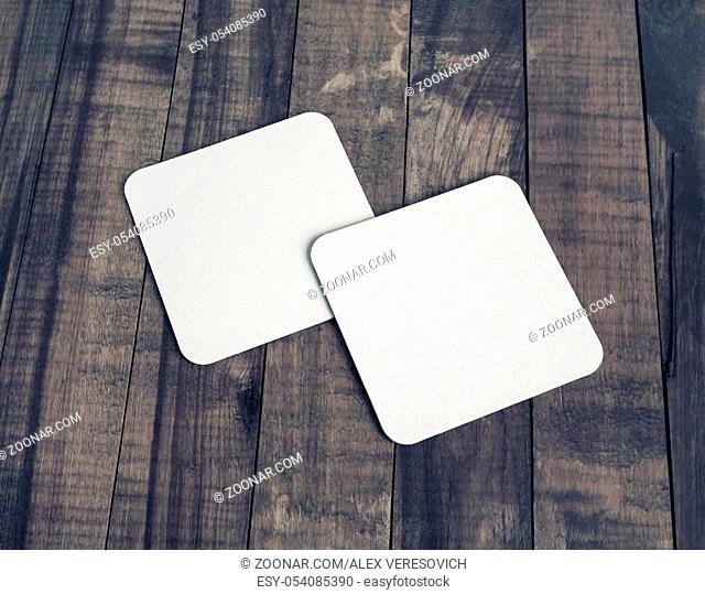 Two blank white beer coasters on wooden table background. Responsive design mockup