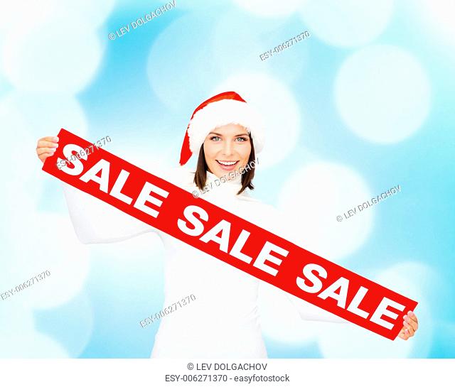 sale, shopping, christmas, holidays and people concept - smiling woman in santa helper hat with red sale sign over blue lights background