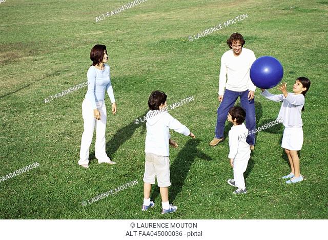 Family playing with ball in grassy field