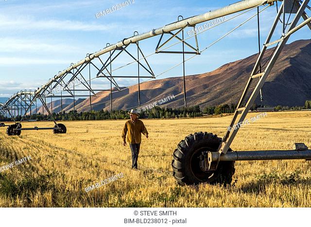 Caucasian farmer walking near irrigation equipment