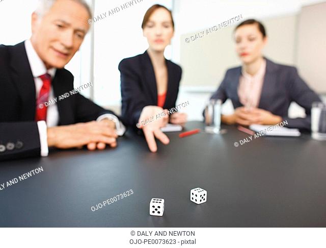 Business people throwing dice on conference room table