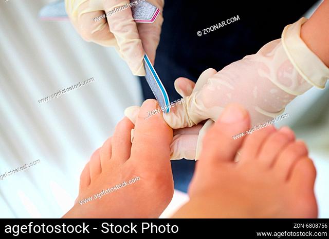 Macro shot of female feet during professional pedicure. Filing procedure at beaty spa salon
