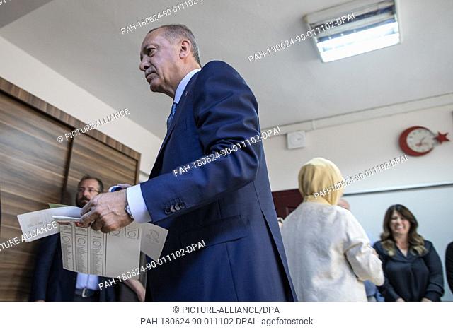 dpatop - Turkish President Tayyip Recep Erdogan holds his ballot papers to vote in Turkey's elections at a polling station, in Istanbul, Turkey, 24 June 2018