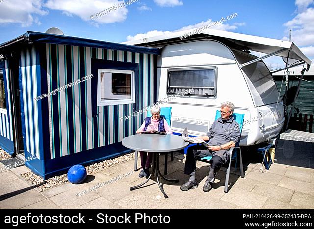 PRODUCTION - 23 April 2021, Lower Saxony, Friesoythe: Permanent campers Marianne and Paul-Jürgen Post sit in front of their caravan at the Wilken family...