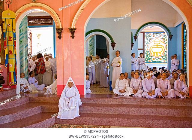 A female CAO DAI PRIEST sits before her followers inside the CAO DAI GREAT TEMPLE, Vietnam, Tay Ninh