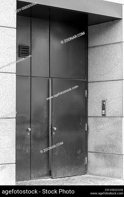 A large metal door is slightly open in black and white