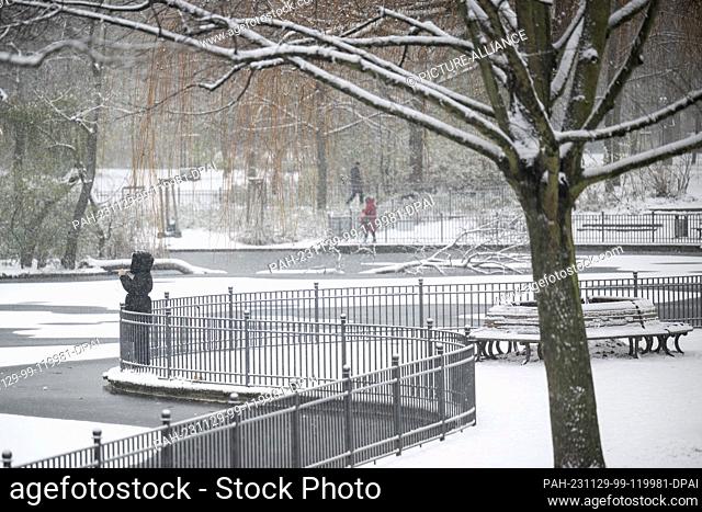 29 November 2023, Berlin: A woman stands by a frozen pond in Volkspark Friedrichshain. Snow and icy conditions continue to grip Berlin and Brandenburg