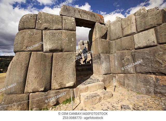 Visitor going through the Stone door at the The Saqsaywaman archaeological complex, a massive fortress of the Incas, overlooking the Inca navel of Cusco, Peru