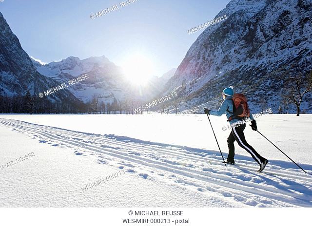 Germany, Bavaria, Senior woman doing cross-country skiing with karwendal mountains in background