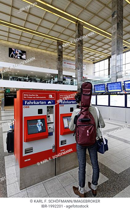 Young man with a guitar on his back buying a train ticket at ticket machine of the OeBB, Oesterreichische Bundesbahnen, Austrian railway, Westbahnhof Station