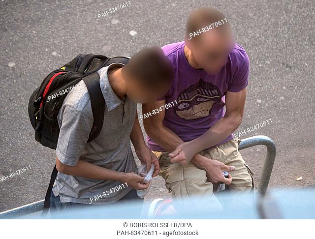 A drug dealer (l) dealing with drugs on an open street in the central station area in Frankfurt/Main, Germany, 6 September 2016