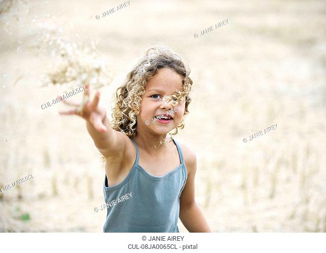 Young girl throwing wheat in field