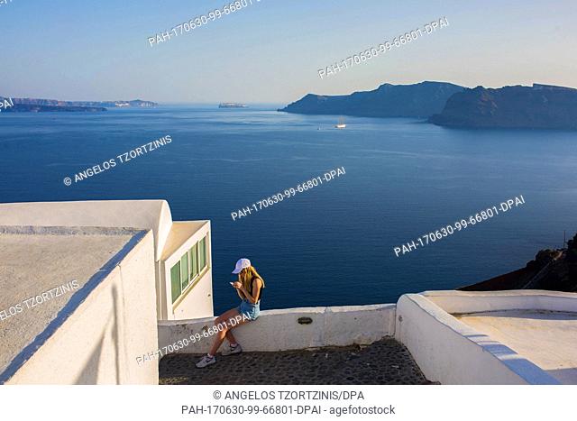 A tourist sits on a wall in the island of Santorini, Greece, 29 June 2017. A heat wave with temperatures of up to 43 degrees Celsius has hit Greece