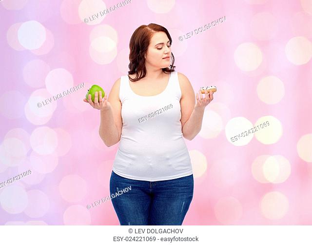 healthy eating, junk food, diet and choice people concept - plus size woman choosing between apple and cookie over pink holidays lights background