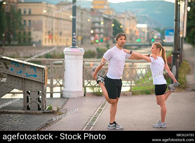 jogging couple warming up and stretching before morning running in the city