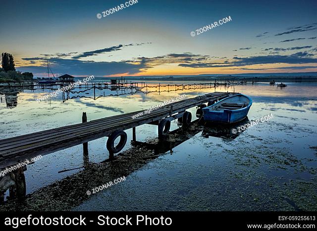 exciting twilight on a shore with pier and boat. Horizontal view