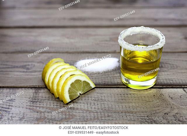 tequila shot with slice lemon and salt on wood background