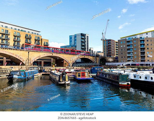 Docklands Light Railway train runs past the apartment buildings around Limehouse Basin Marina in Docklands, London, England