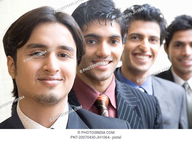 Portrait of four businessmen smiling in a row