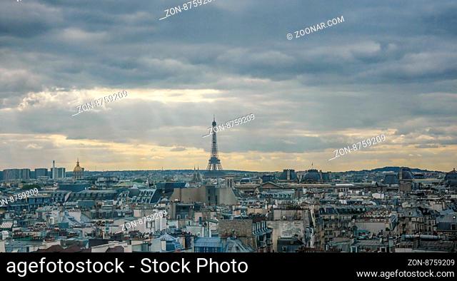 Small Eiffel Tower at horizon in France with sprawling urban landscape in foreground