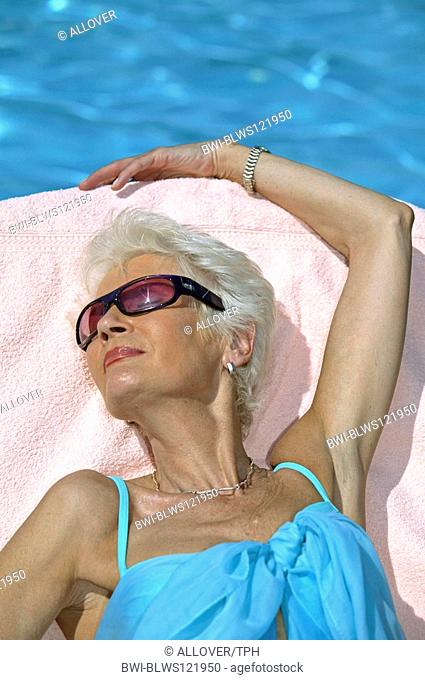 whitehaired woman sunbathing at the pool
