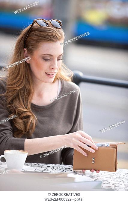 Young woman taking note out of her purse