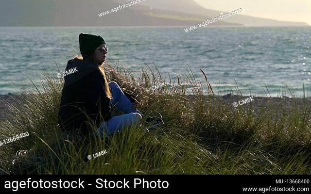 Pretty girl rests in the reed grass near the ocean