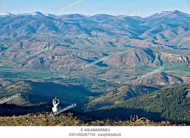 Woman meditating on rock with scenic view from above. North Cascades near Winthrop. Washington State. United States of America