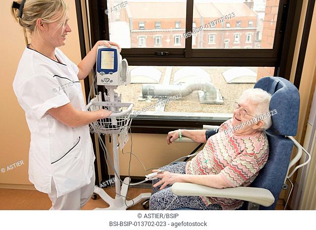Reportage in the Geriatrics service in Saint-Vincent de Paul hospital in Lille, France. A nurse checks a patient's blood pressure in her hospital room