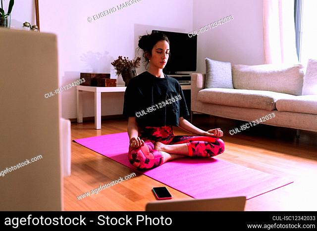 Young woman practicing yoga and meditation at home